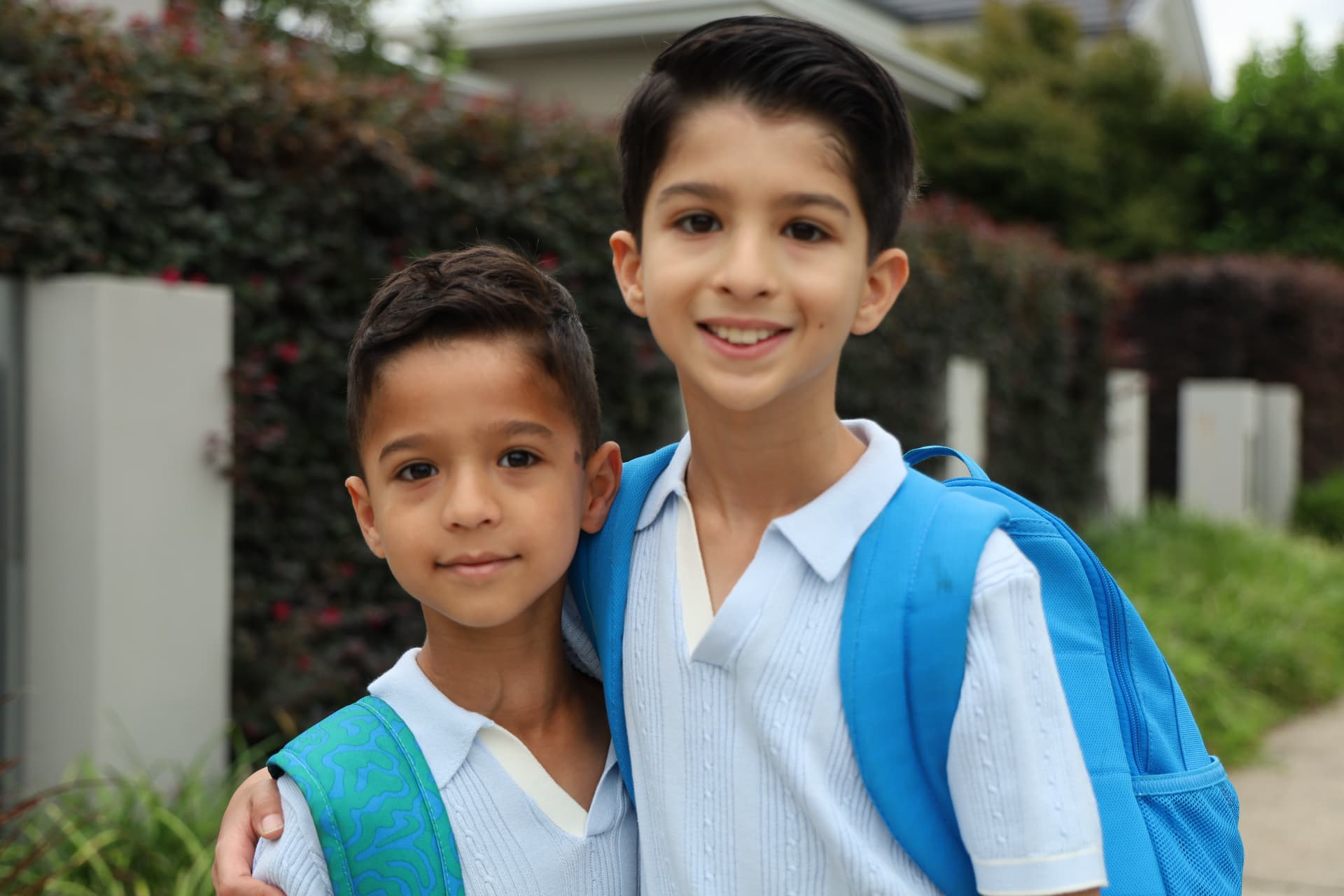 Brothers Zhivan and Artan smiling outside in their school uniforms